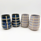 Four ceramic tumblers with checkered pattern on a white background
