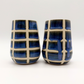 Two ceramic tumblers with blue and white grid pattern on a white background