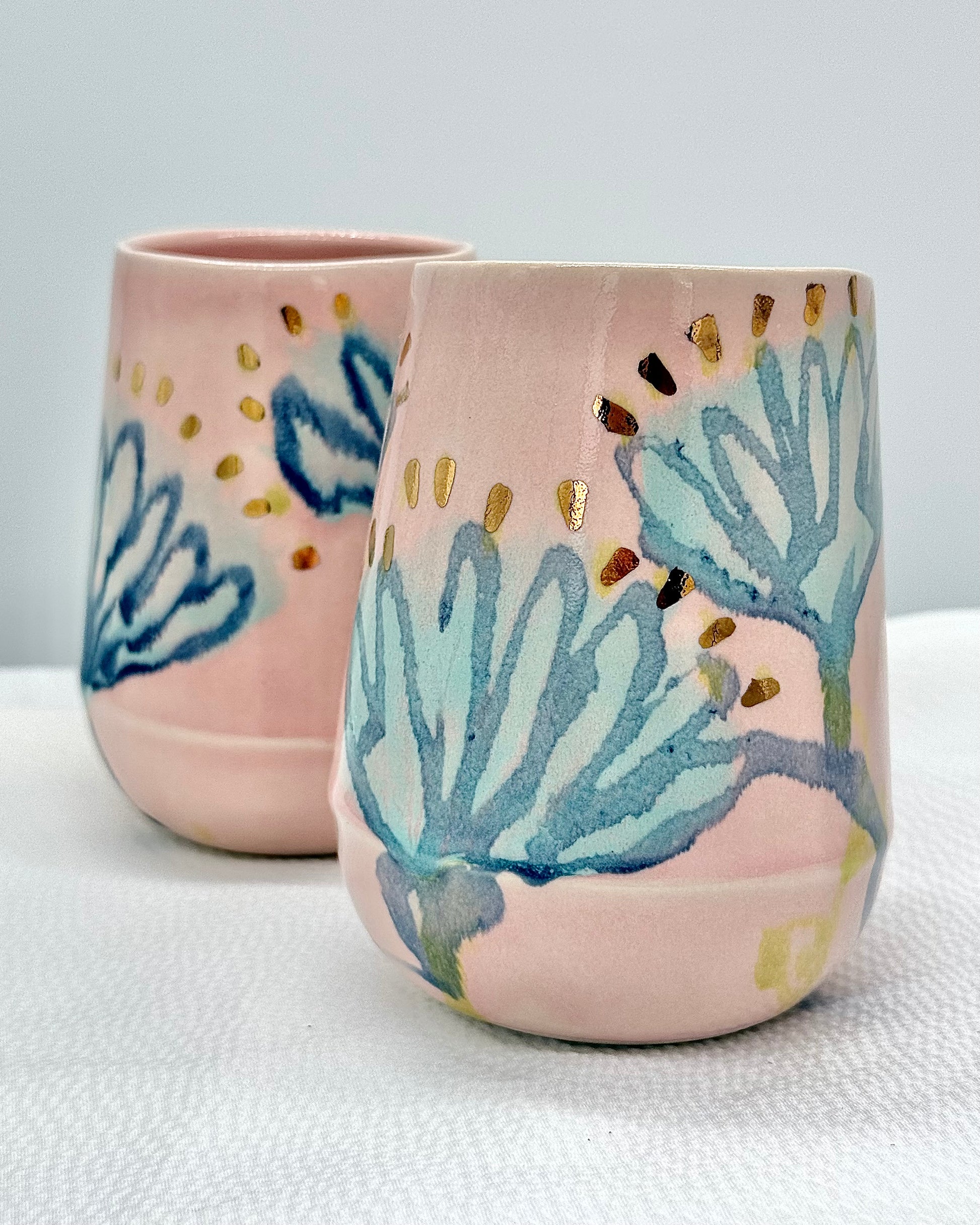 Two ceramic tumblers with floral designs on a light background