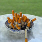 handmade blue-and-white spongeware ceramic ashtray sculpture filled with orange-tipped cigarette butts.